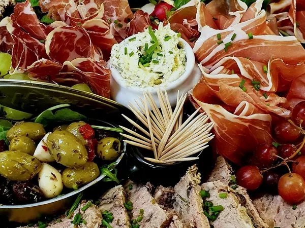 Plateau de charcuterie et d'antipasti de la maison : coppa, jambon cru, ricotta fouettée, olives, terrine et raisin