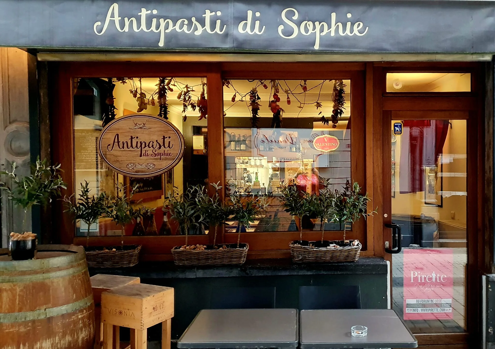 La devanture du Bar à manger : enseigne en bois, piments et aulx séchés en vitrine, oliviers en pot