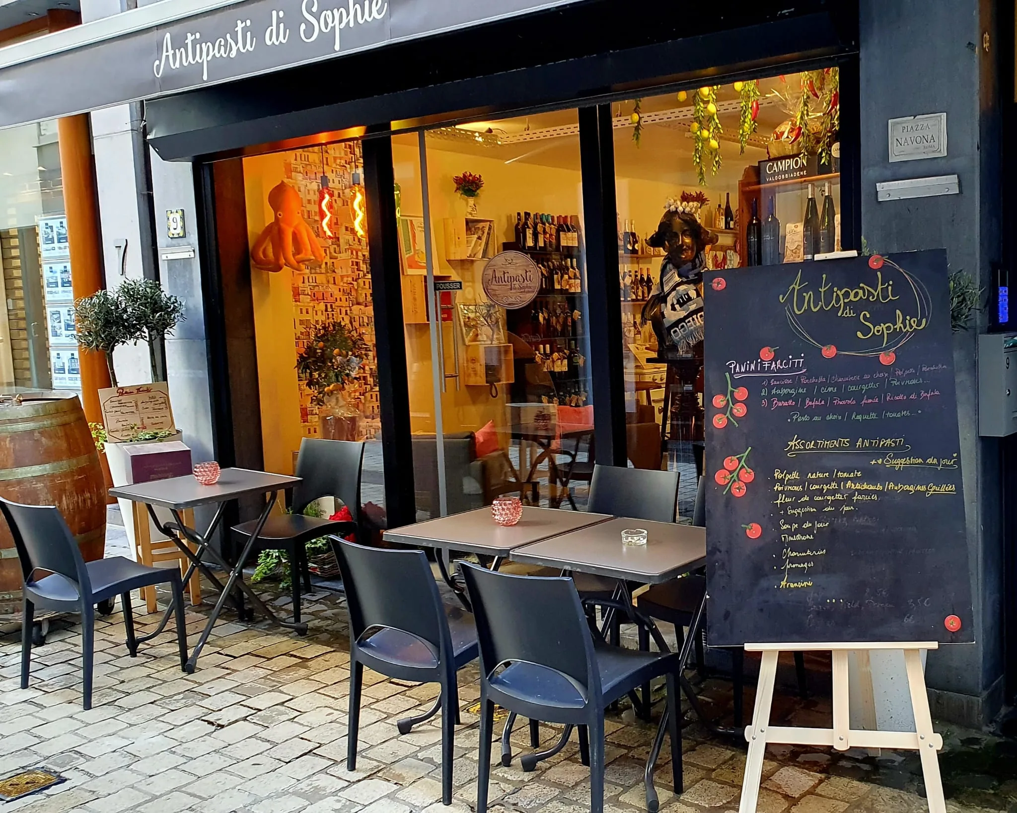 La devanture du Resto, la terrasse en journée et le tableau des plats devant la façade